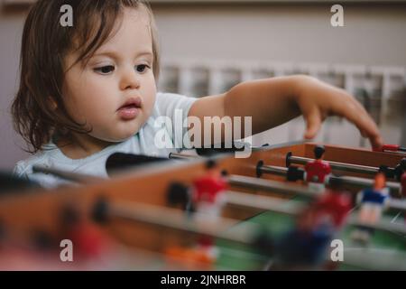 Bambina con suo fratello che gioca a calcio balilla per rilassarsi in vacanza a casa. Relax estivo. Foto Stock