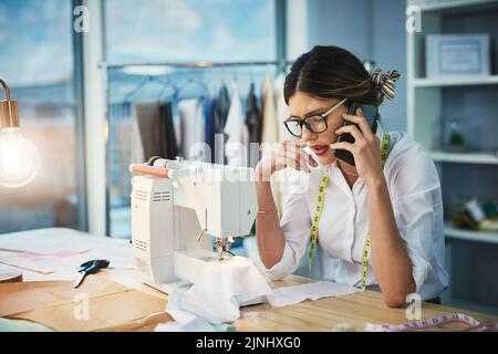 Siete sicuri di questi cambiamenti. Un giovane stilista attraente fare una telefonata mentre lavora nel suo studio di design. Foto Stock