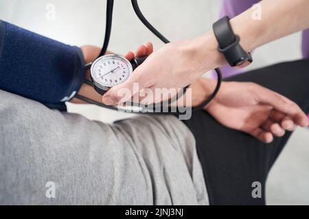 Il medico le mani che controllano la pressione sanguigna del paziente in clinica Foto Stock