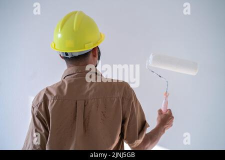 Gli uomini dipingono il colore degli interni con la pittura a rullo su sfondo bianco Foto Stock