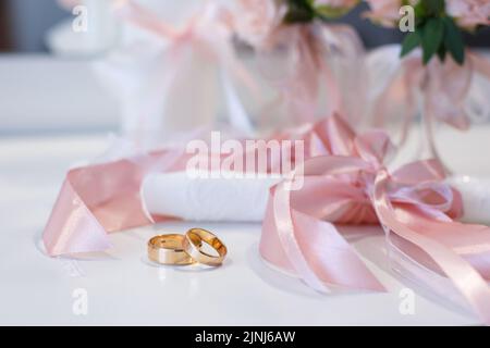 Dettagli del matrimonio, simbolo dell'amore e del matrimonio. Primo piano degli anelli universali d'oro che sdraiano sul tavolo. Concetto di simboli e attributi di matrimonio. Foto Stock