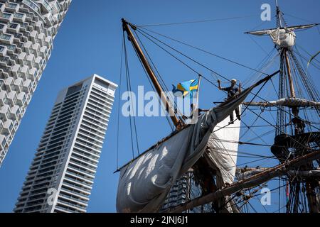 L'equipaggio della nave a vela replica, Goteborg, effettua riparazioni e manutenzione mentre attraccato sotto le alte torri di South Quay, Canary Wharf nei Docklands di Londra, durante la sua visita di quattro giorni alla capitale prima di continuare la sua spedizione di due anni intorno al mondo a Shanghai, Cina, il 9th agosto 2022, A Londra, Inghilterra. I londinesi sono invitati a visitare i ponti di questo facsimile della nave originale che affondò al largo della costa svedese nel 1745. Il suo carico principale sarebbe stato il tè, porcellana, erbe e seta sulla rotta della Cina. (Foto di Richard Baker / in Pictures via Getty Images) Foto Stock