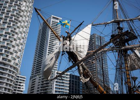 L'equipaggio della nave a vela replica, Goteborg, effettua riparazioni e manutenzione mentre attraccato sotto le alte torri di South Quay, Canary Wharf nei Docklands di Londra, durante la sua visita di quattro giorni alla capitale prima di continuare la sua spedizione di due anni intorno al mondo a Shanghai, Cina, il 9th agosto 2022, A Londra, Inghilterra. I londinesi sono invitati a visitare i ponti di questo facsimile della nave originale che affondò al largo della costa svedese nel 1745. Il suo carico principale sarebbe stato il tè, porcellana, erbe e seta sulla rotta della Cina. (Foto di Richard Baker / in Pictures via Getty Images) Foto Stock