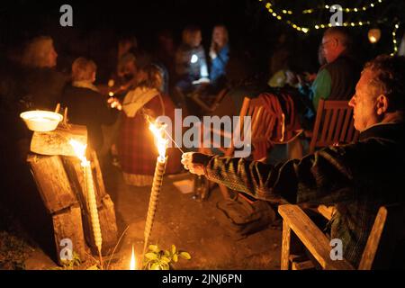 Un festaiolo fonde un marshmallow sulle fiamme di un fuoco durante una festa notturna nel Sussex orientale, il 6th agosto 2022, a Horns Cross, Inghilterra. Foto Stock