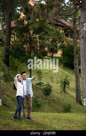 Felice giovane coppia asiatica che guarda in lontananza mentre cammina nel bosco Foto Stock
