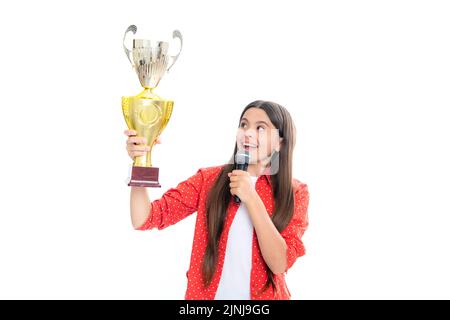 Ragazza adolescente in possesso di un trofeo microfono discorso. Il bambino vincitore ha vinto il concorso, celebrando il successo e la vittoria, il premio di successo. Foto Stock