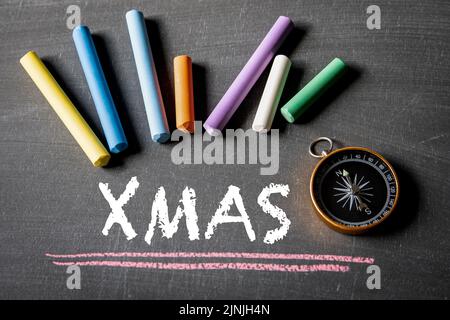Natale, concetto di Natale. Testo e bussola su una lavagna a gesso. Foto Stock