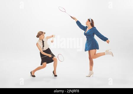 Ritratto di giovani donne belle ed eleganti che giocano a badminton, in posa isolata su sfondo bianco studio Foto Stock