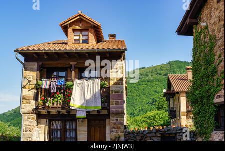 Balconi di vecchie case in pietra con abiti appesi al sole. Foto Stock