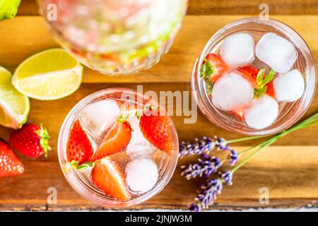 Bevanda estiva con frutta fresca, fragola, lime e ghiaccio, posta su una scrivania di legno Foto Stock