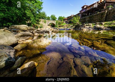 Ruscello di montagna con acqua cristallina che passa accanto a una città. Barcena Mayor Santander. Foto Stock