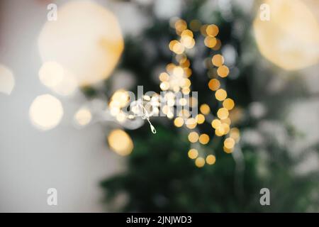 Buon Natale e felice anno nuovo! Le eleganti luci natalizie si avvicinano a uno sfondo molto malizio. Luce calda dorata bokeh e luce garland primo piano. Foto Stock