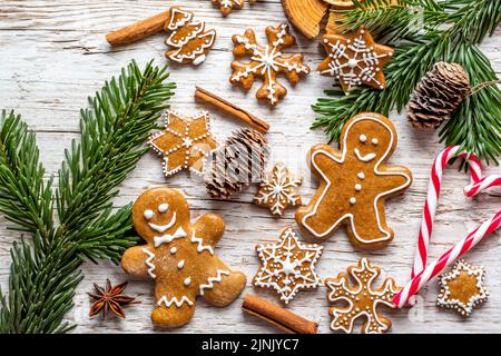 Il pan di zenzero di Natale e i dolci sono posti sulla scrivania di legno. Biscotti e cibi dolci a forma di stelle e fiocchi di neve. Tema invernale, stile rustico. Pino Foto Stock