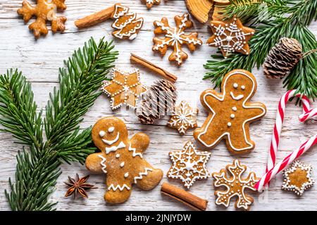 Il pan di zenzero di Natale e i dolci sono posti sulla scrivania di legno. Biscotti e cibi dolci a forma di stelle e fiocchi di neve. Tema invernale, stile rustico. Pino Foto Stock