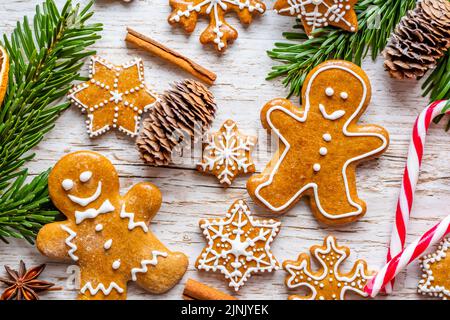 Il pan di zenzero di Natale e i dolci sono posti sulla scrivania di legno. Biscotti e cibi dolci a forma di stelle e fiocchi di neve. Tema invernale, stile rustico. Pino Foto Stock