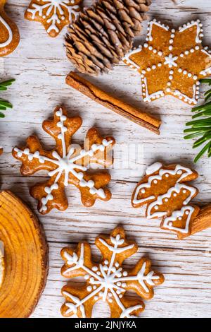 Il pan di zenzero di Natale e i dolci sono posti sulla scrivania di legno. Biscotti e cibi dolci a forma di stelle e fiocchi di neve. Tema invernale, stile rustico. Pino Foto Stock