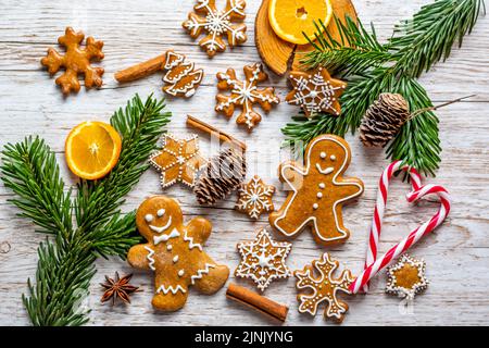 Il pan di zenzero di Natale e i dolci sono posti sulla scrivania di legno. Biscotti e cibi dolci a forma di stelle e fiocchi di neve. Tema invernale, stile rustico. Pino Foto Stock