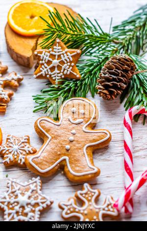 Il pan di zenzero di Natale e i dolci sono posti sulla scrivania di legno. Biscotti e cibi dolci a forma di stelle e fiocchi di neve. Tema invernale, stile rustico. Pino Foto Stock