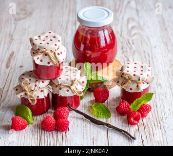 La marmellata di lamponi in piccoli bicchieri è posta su una scrivania di legno. Marmellata fatta in casa di lamponi freschi. Cucina fresca e sana. Foto Stock