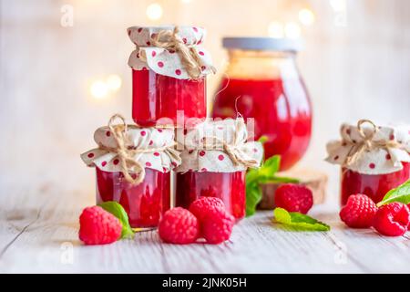 La marmellata di lamponi in piccoli bicchieri è posta su una scrivania di legno. Marmellata fatta in casa di lamponi freschi. Cucina fresca e sana. Foto Stock