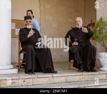 Albania, 12 maggio 2022 - i sacerdoti ortodossi siedono sulla sedia di fronte alla loro chiesa. Foto Stock