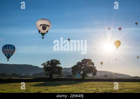 Le mongolfiere prendono il volo durante la Bristol International Balloon Fiesta che si tiene a Bristol, Regno Unito, la mattina presto del 12 agosto 2022. Le mongolfiere sono decollo al primo semaforo da Ashton Court, come parte della famosa “Mass Ascent”. Il vento ha preso i palloncini Sud Ovest su Nailsea e Backwell. Molti dei quali sono atterrati nei campi vicini e hanno trattato la gente del posto ad una vista stupefacente di mattina presto. (Foto di Chris Pearce/Sipa USA) Foto Stock