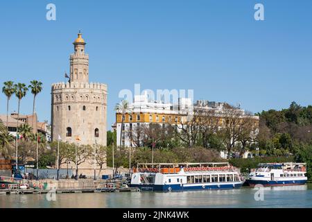 Barche per escursioni ormeggiate al molo della torre di avvistamento del 13th ° secolo Torre del Oro a Siviglia, Spagna Foto Stock