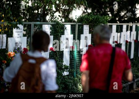 Berlino, Germania. 12th ago, 2022. Passers-by guarda le bianche croci commemorative su Ebertstrasse, nel quartiere governativo di Berlino. Il 13 agosto 2022 segna il 61st° anniversario della costruzione del Muro. Credit: Fabian Sommer/dpa/Alamy Live News Foto Stock