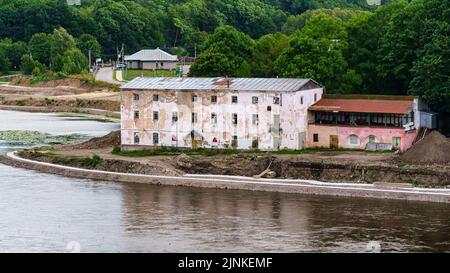 Edifici residenziali abbandonati sulla riva del fiume al confine russo-estone. Foto Stock