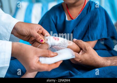 Primo piano colpo medico legando la benda a bambini preoccupati feriti mano in ospedale - concetto di medicare, infanzia mischief e pronto soccorso medico. Foto Stock