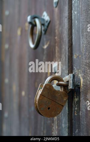 Particolare del vecchio lucchetto su porta in legno e vecchio batticalcagno. Foto Stock