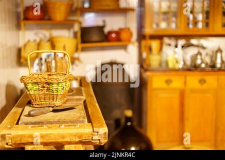 Cestino di vimini e utensili molto vecchi in cucina in legno e look vintage. Foto Stock
