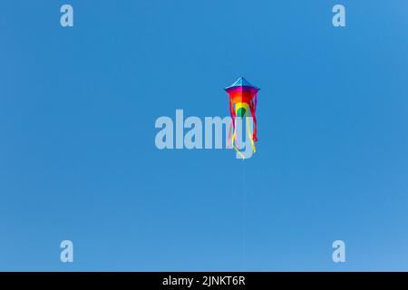 Un aquilone arcobaleno che vola in alto nel cielo Foto Stock