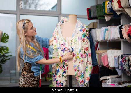 Nell'officina del sarto, un designer di abbigliamento dispone il tessuto su un manichino. Foto Stock