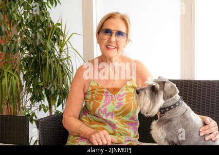 Donna anziana felice con il suo cane all'interno della sua casa in terrazza. Foto Stock