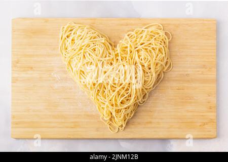 Pasta decorativa a forma di cuore ancora vita formata da pasta ricoperta di pomodori, basilico Foto Stock