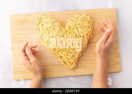 Pasta decorativa a forma di cuore ancora vita formata da pasta ricoperta di pomodori, basilico Foto Stock
