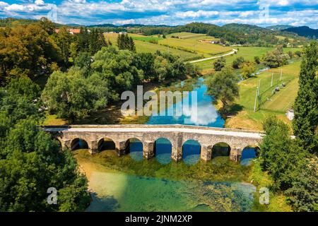 Veduta aerea del vecchio ponte di pietra sul fiume Dobra, Croazia Foto Stock