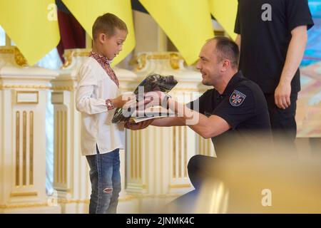 Kiev, Ucraina. 12th ago, 2022. Serhiy Kruk, capo del servizio di emergenza dello Stato ucraino, si congratula con Yegor Shemet, partito, durante un evento per celebrare i soccorritori dei bambini e gli eroi di guerra per la Giornata Internazionale della Gioventù nella Sala Bianca degli Eroi al Palazzo Mariinskyi, 12 agosto 2022 a Kyiv, Ucraina. Credit: Sarsenov Daniiar/Ukraine Presidency/Alamy Live News Foto Stock