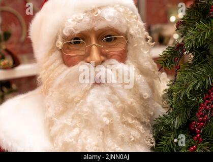 Bambola Santa Clause a grandezza naturale accanto a un albero di Natale, primo piano del viso con gli occhiali con bordo in filo metallico Foto Stock