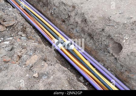 installazione di infrastrutture per cavi elettrici sotterranei. Cantiere con molti cavi di comunicazione protetti in tubi. elettrico e alta-spe Foto Stock