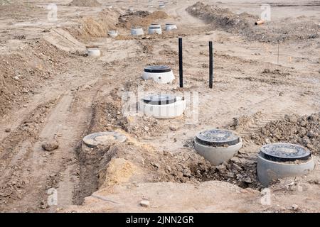 Le botole fognarie hanno sviluppato tubi di drenaggio in calcestruzzo tra grandi aree residenziali. Nuova fognatura sanitaria, impianti di scarico in cantiere. Foto Stock