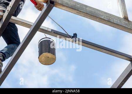 Costruzione non sicura di lavoratori mentre dipingono tubo di acciaio di alto edificio. Foto Stock