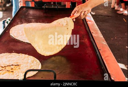 Tortillas tradizionali Nicaraguane fatte a mano, tortillas di mais tradizionali fatte a mano sulla griglia. Mani preparare le tortillas tradizionali sulla griglia, primo piano Foto Stock