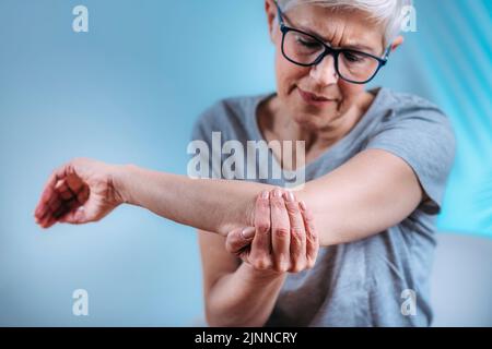 Donna anziana con gomito doloroso Foto Stock