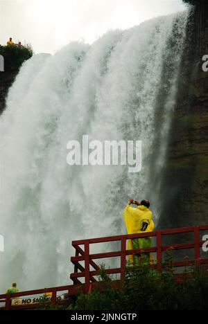 Due visitatori nei laghetti gialli potranno ammirare la potenza delle cascate del Niagara dalla base durante il tour della grotta dei venti Foto Stock