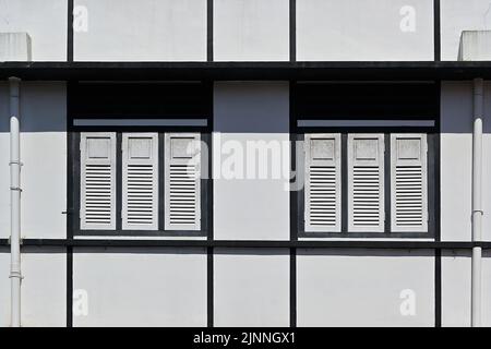Facciata di un edificio pre-bellico rinnovato in uno stile art deco moderno essenziale con persiane in legno e sfiati di ventilazione, Asia sudorientale Foto Stock