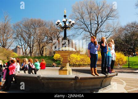 Un gruppo di ragazze adolescenti si trova sul bordo di una fontana vuota in una giornata primaverile a Central Park, New York City Foto Stock