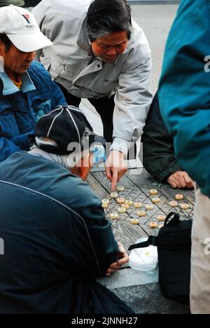 Una folla di amici anziani discute la prossima mossa in un gioco xiangqi, un antico gioco di strategia cinese simile agli scacchi, in un incontro a San Francisco Foto Stock