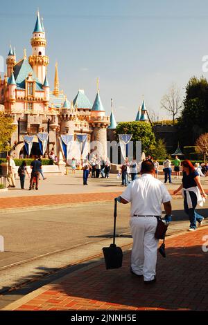 Un membro del cast di Disneyland passeggia per il parco a tema, vicino al Castello di Cenerentola, raccogliendo la lettiera e assicurandosi che il parco sia tenuto pulito Foto Stock